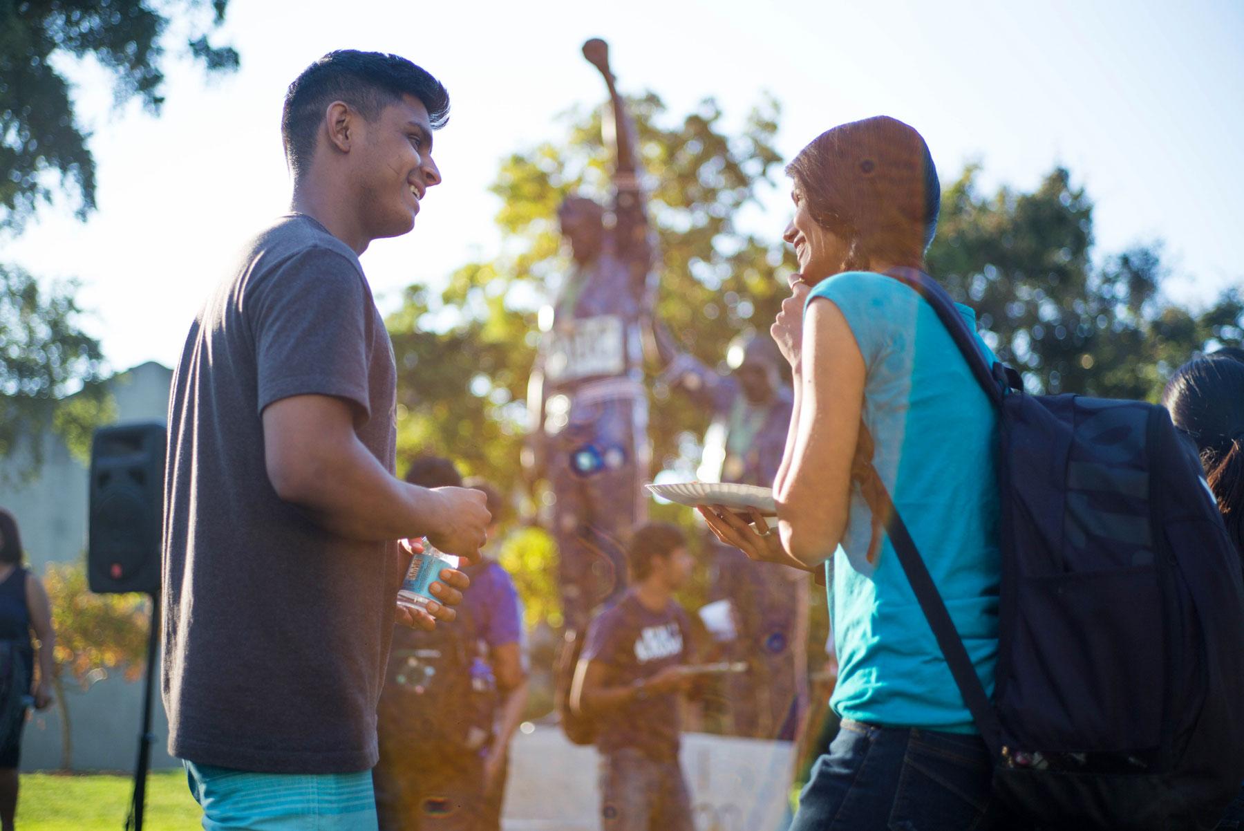 two students speaking in front of statue