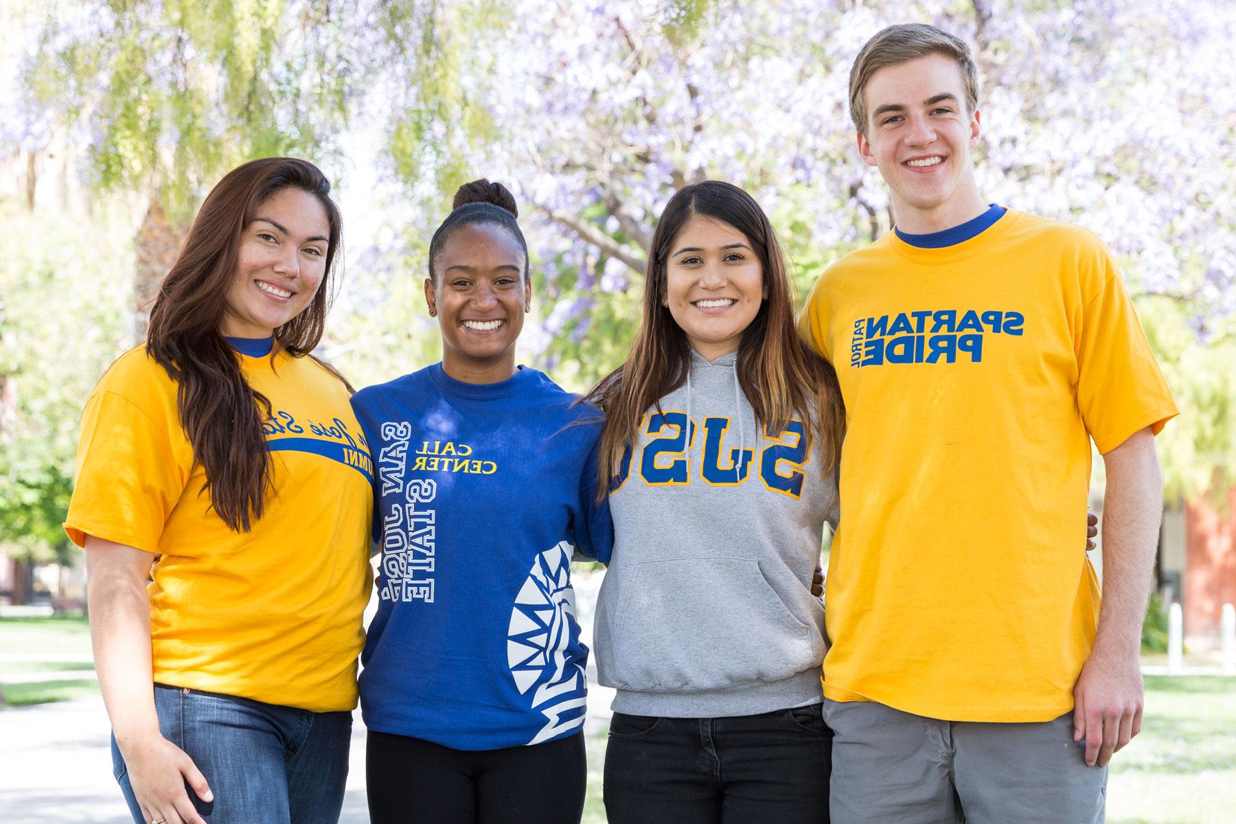 Four diverse students wearing 圣何塞州立大学 spartan shirts smile and pose for a photo. 