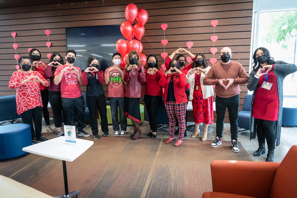 十大菠菜软件 president with students and staff making a heart sign with their hands.