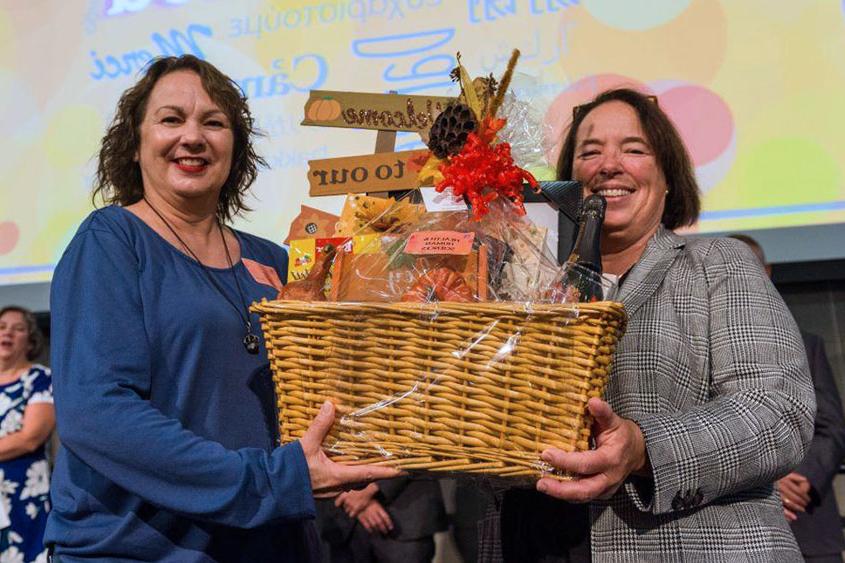 Two staff members holding up a gift basket.